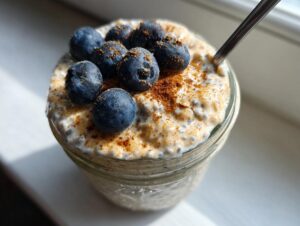 Close-up of a creamy, high-protein chia pudding topped with fresh blueberries and a sprinkle of cinnamon.