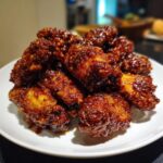 A pile of crispy, dark, and glossy korean fried chicken wings coated in a sticky sauce on a white plate.