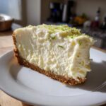 A thick slice of creamy lemon lime no bake cheesecake with a graham cracker crust, topped with lime zest.