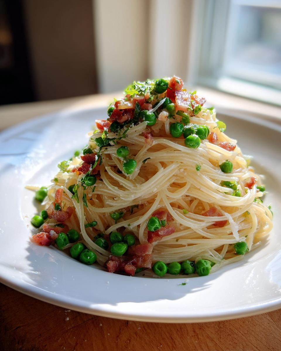 A beautifully plated serving of light pasta with pancetta & peas, topped with fresh herbs, catching bright natural light.