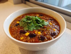 A close-up of a steaming bowl of Mexican quinoa soup, rich with beans, corn, and topped with fresh cilantro.