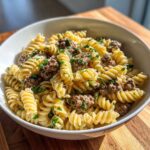 Close-up of a white bowl filled with one pot creamy beef and garlic pasta, featuring fusilli noodles and ground beef.