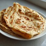 A stack of golden, slightly charred flatbreads ready to be used as a cottage cheese wrap.