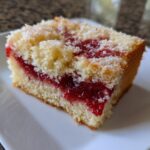 Close-up of a moist slice of sugar free strawberry jam snack cake showing layers of yellow cake and bright red jam filling.
