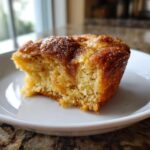 Close-up of a warm snickerdoodle cobbler slice showing a soft, cake-like interior and a sugary cinnamon topping.