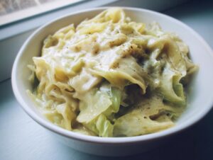 Close-up of tender cabbage coated in a creamy sauce, seasoned with pepper, representing Cabbage Alfredo.