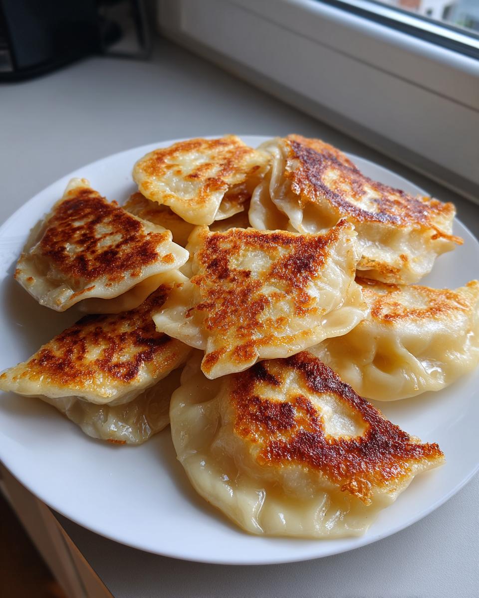 A plate piled high with golden-brown, pan-fried cabbage dumplings, showing crispy edges.
