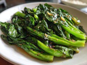 Close-up of vibrant green, glossy sautéed bok choy seasoned with garlic and sesame seeds.