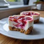 A close-up of a Strawberry Rhubarb Mini Cheesecake showing the graham cracker crust and swirled fruit topping.